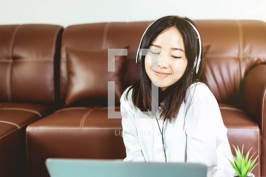a woman listening to headphones while on a computer 