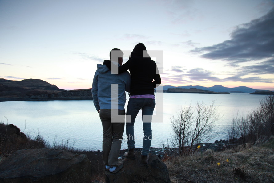 a couple looking out at a lake at sunset 