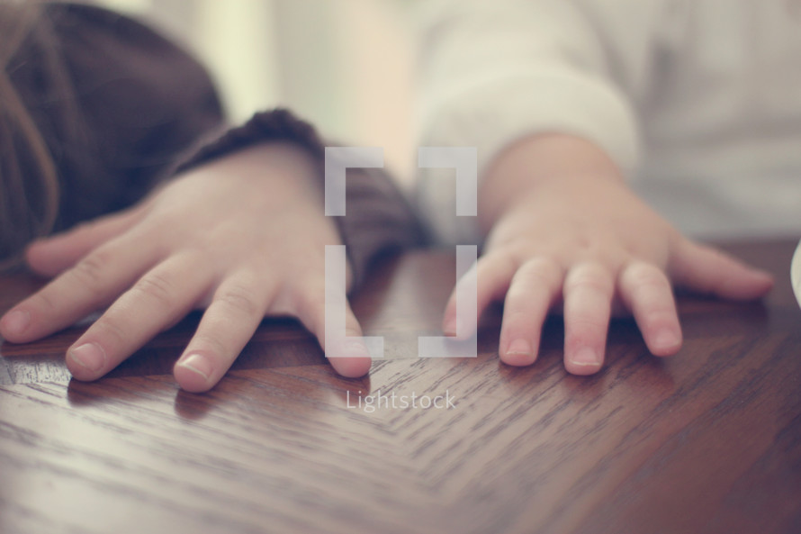 Children's hands on a wooden table.