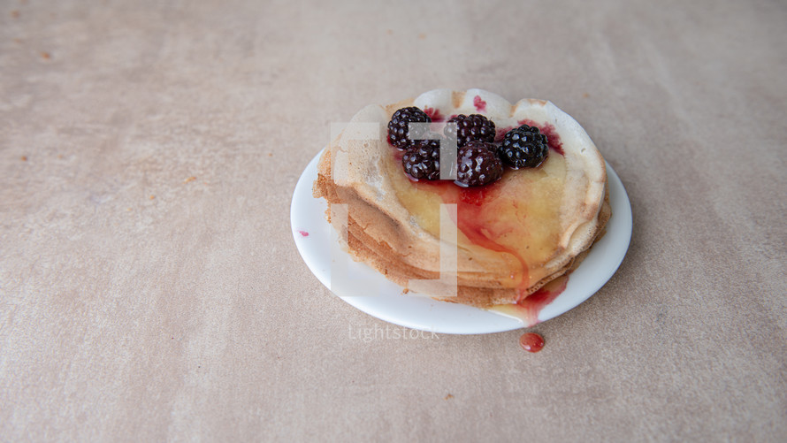 Stack of thin pancakes poured with honey and decorated with fresh blueberries side view with selective focus. The concept of Russian holiday Maslenitsa