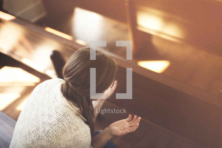 a woman praying in church pews 