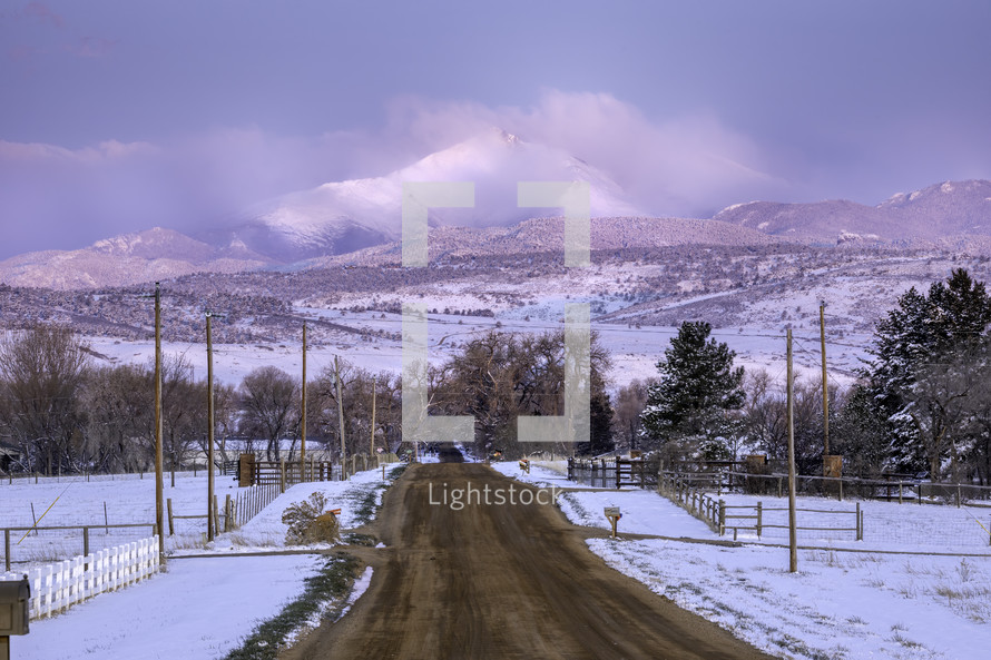 A Dirt Urban Road leading to a Snow Capped Longs Peak Mountain after a fresh snow fall