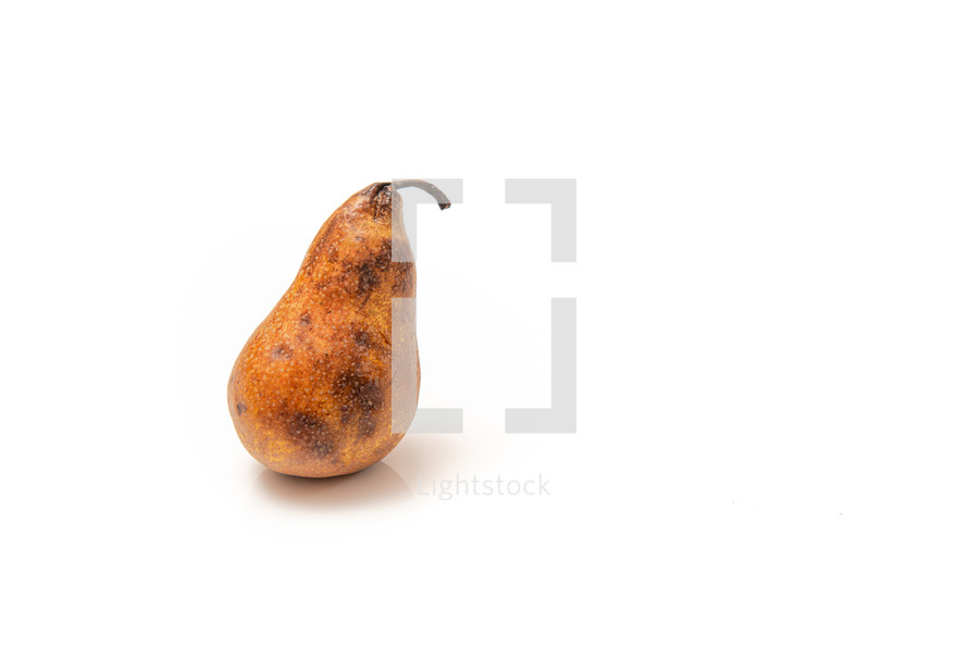 overripe pear with dark spots on a white background
