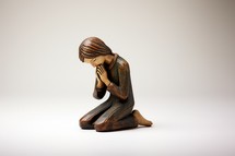 Wooden statuette of a praying woman on a white background