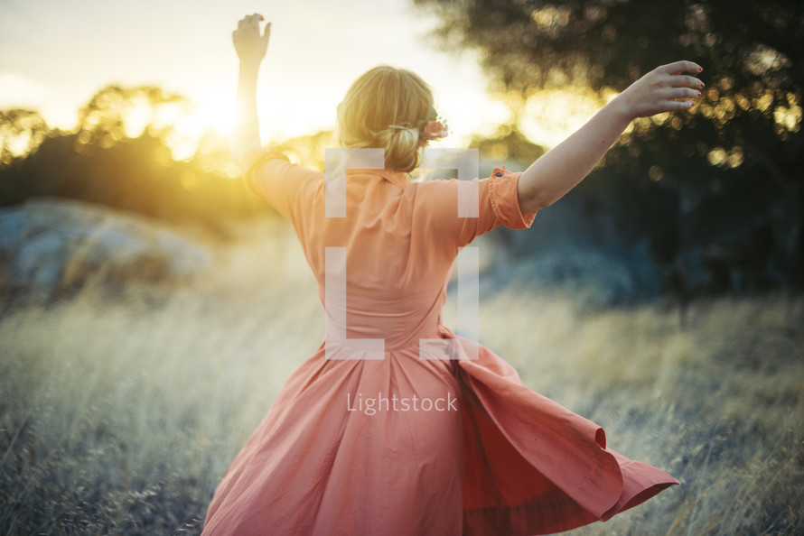 a woman in a dress dancing in a field 
