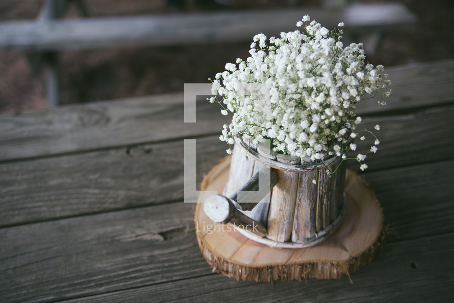 Baby's breath flowers in a bucket on a wood table.