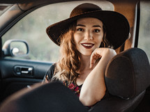 a woman in a hat riding in a car 