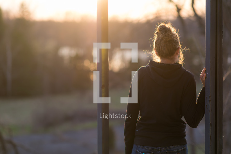 a teen girl standing outdoors at sunset 