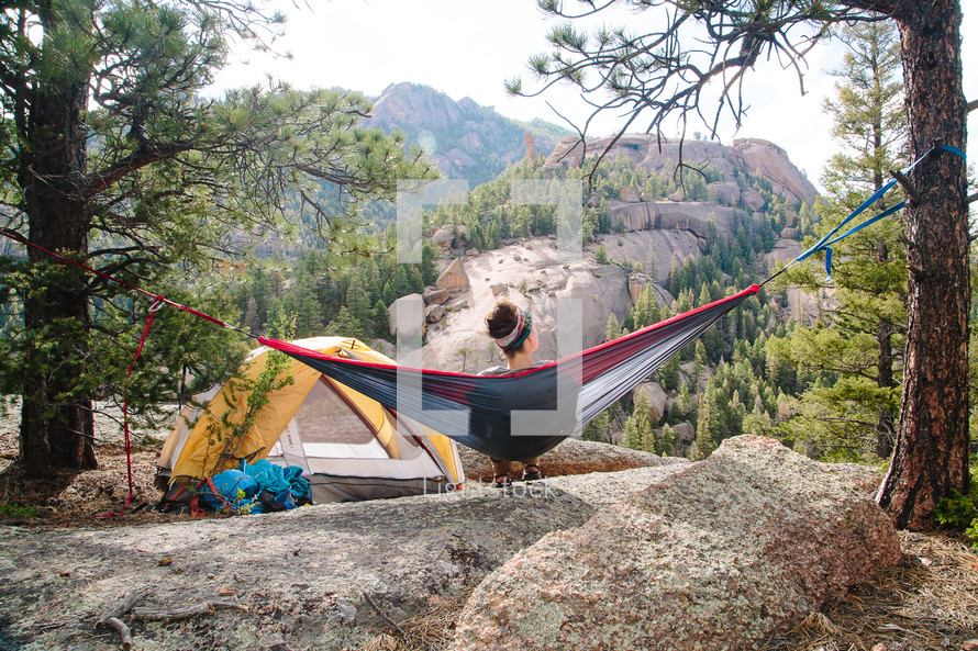 a woman camping sitting in a hammock 