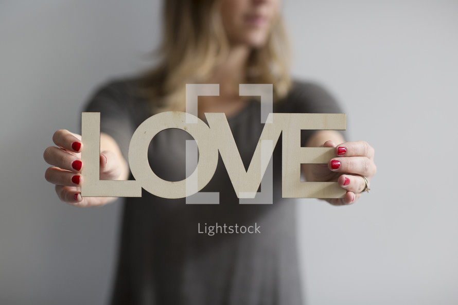 a woman holding a sign of the word love 