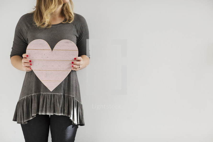 a woman holding a wooden heart