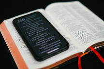 Bible app on a cellphone on the pages of a Bible 