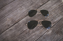 Two matching pairs of sunglasses on wood