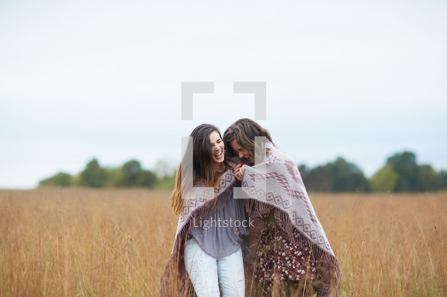 friends under a blanket standing in a field 