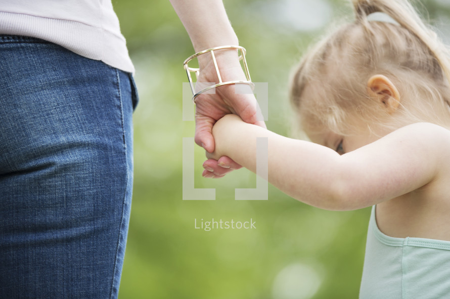 a toddler girl holding mother's hand 
