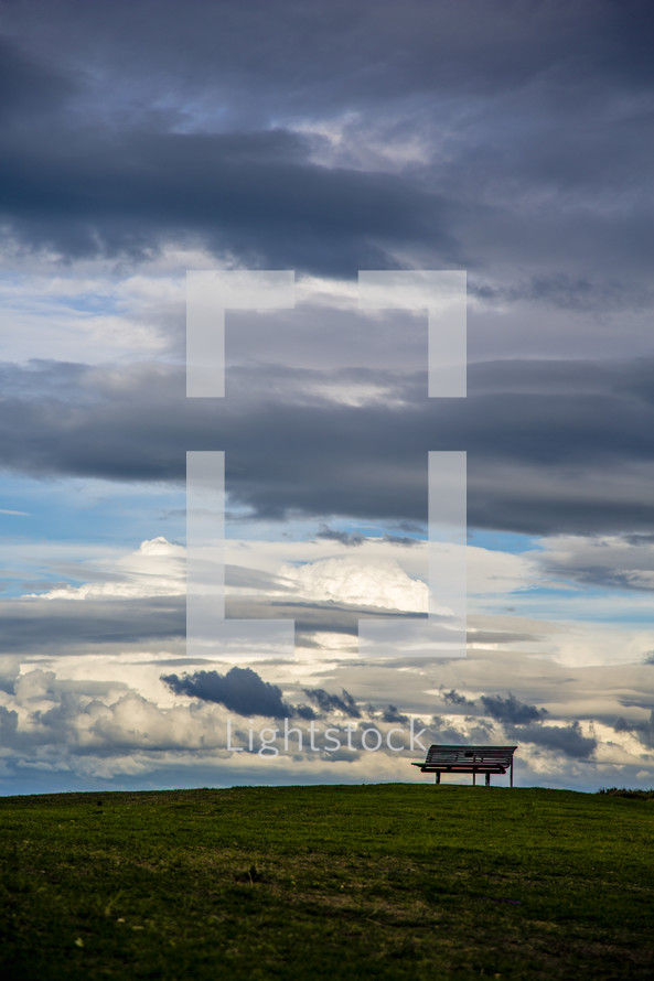 park bench on a mountain top under clouds 