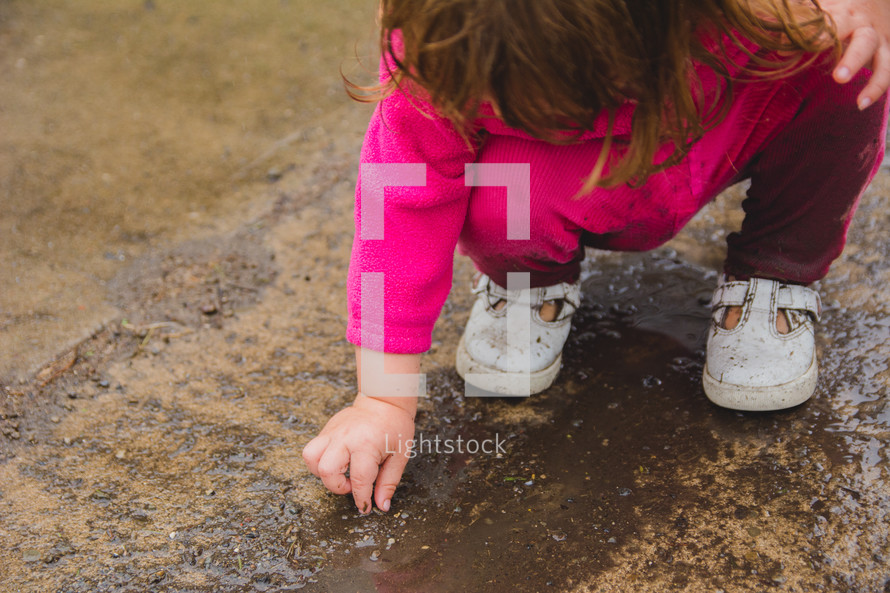 a toddler playing in mud 