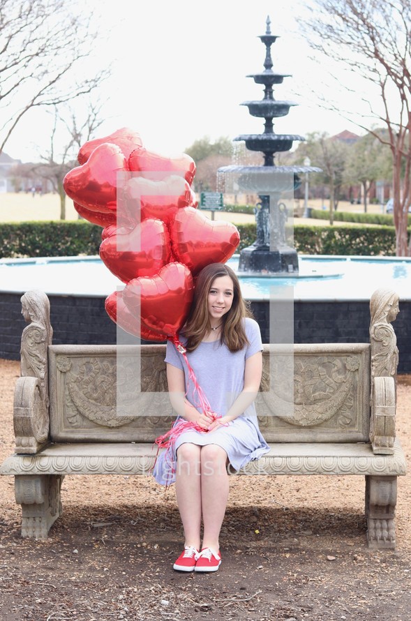 teen girl holding heart shaped red balloons 