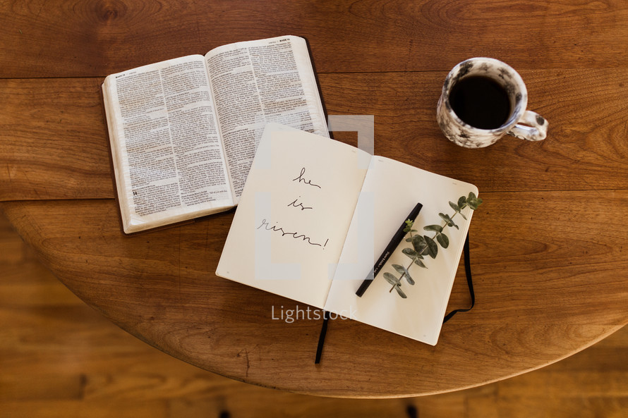 he is risen written in a journal on a wood table 