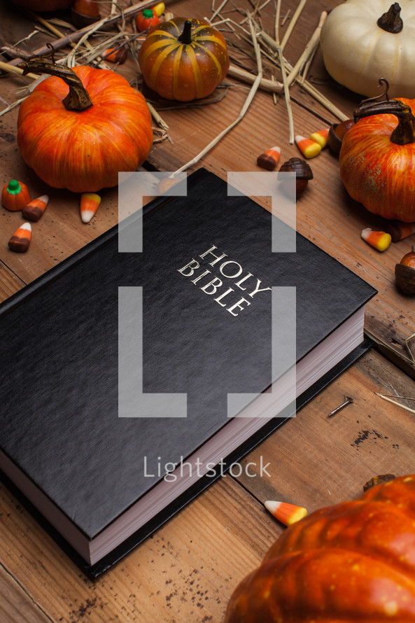 Holy Bible on a wood table surrounded by pumpkins