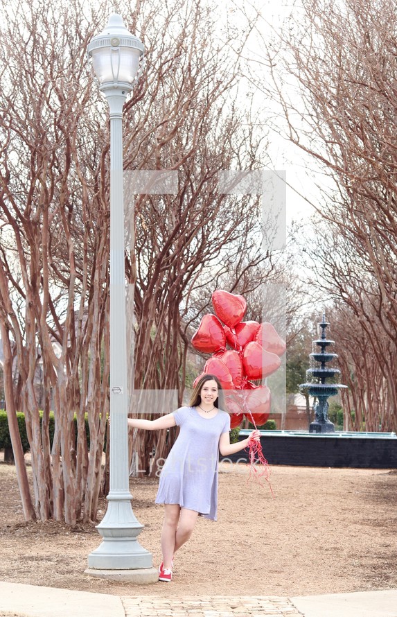 teen girl holding heart shaped helium balloons 
