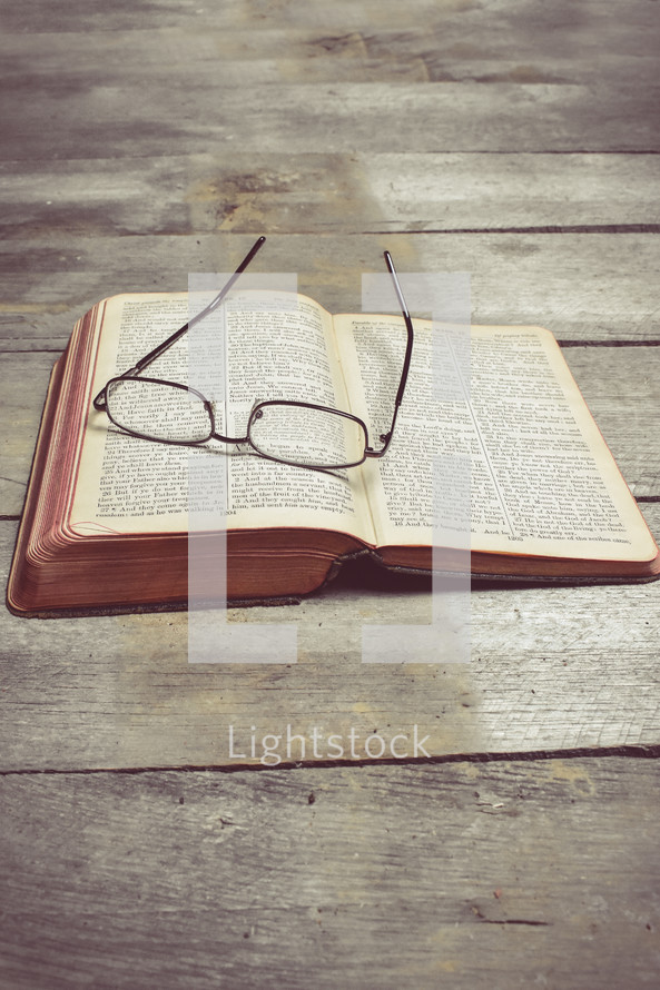 reading glasses on the pages of a Bible 