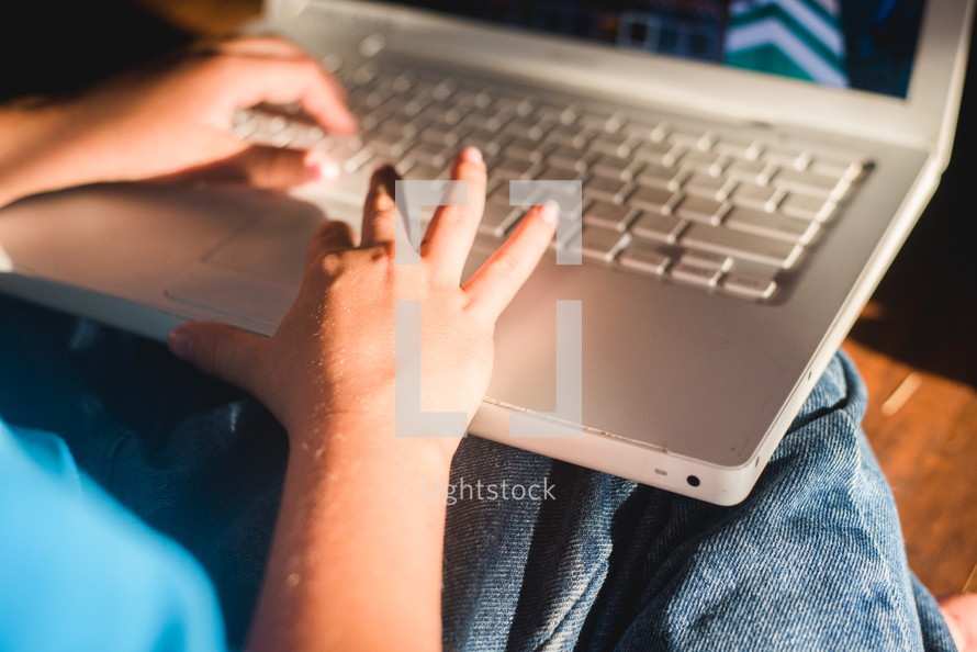 a child typing on a laptop 