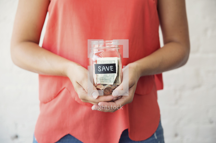 woman holding a save money jar 