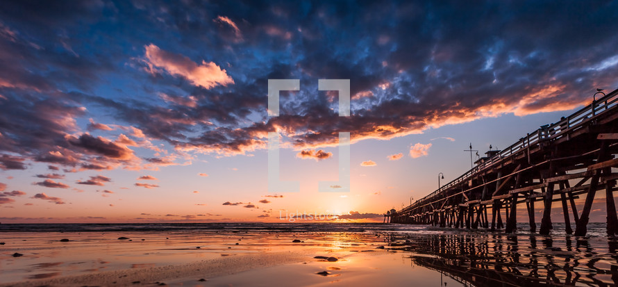 pier at sunset along a beach 