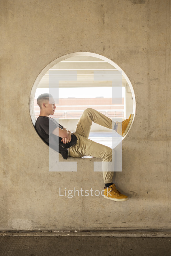 a teenage boy sitting in a circular window 