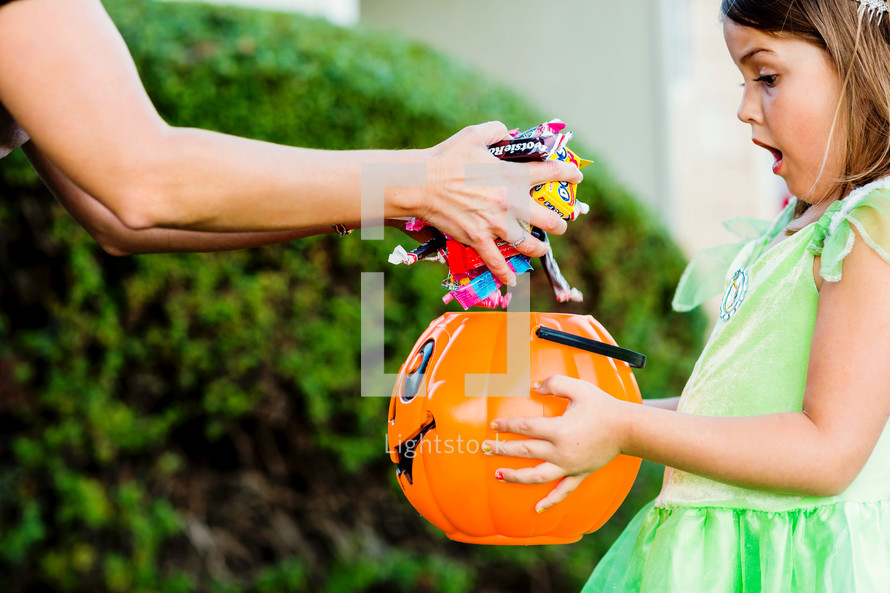 a girl child trick-or-treating getting lots of candy 