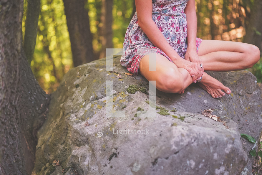 a woman sitting on a rock 