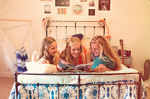 sisters reading a magazine on a bed 