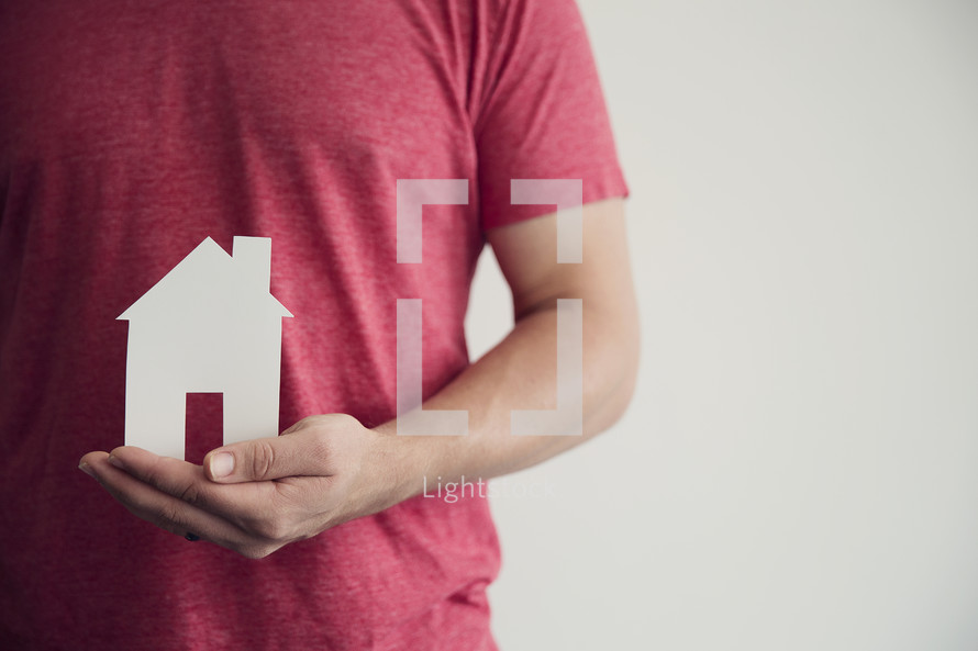 man holding a paper cutout of a house 