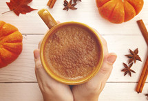 warming hands on a mug of pumpkin spiced coffee 