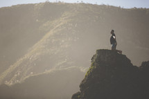 a man kneeling on a rock peak 