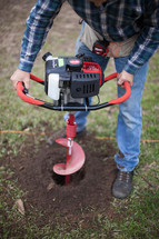 man drilling a hole in soil 