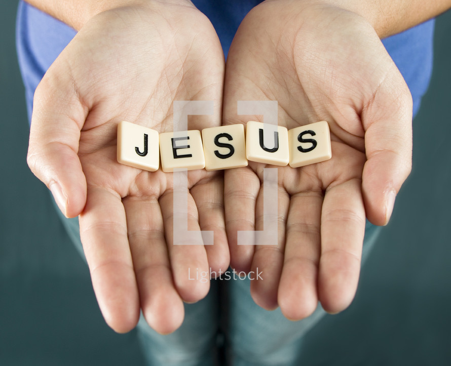 A girl holds out her hands with the word "JESUS"