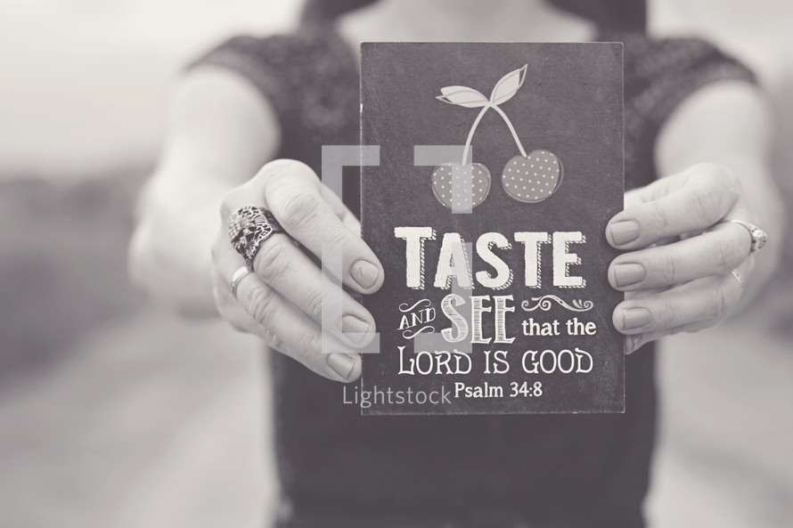 woman holding a sign that reads, Taste and see that the lord is good, Psalm 34:8