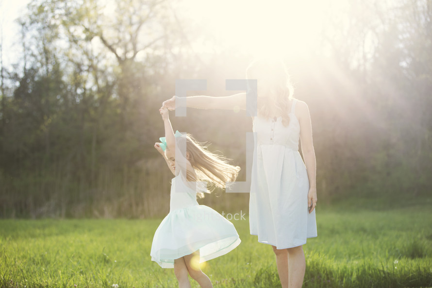mother and daughter dancing outdoors in sunlight 