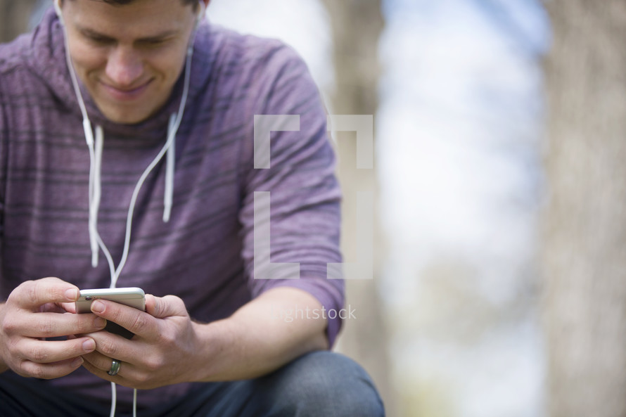 a man listening to music outdoors with earbuds 