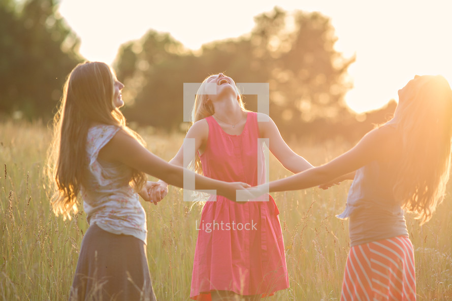 women holding hands in a field laughing 