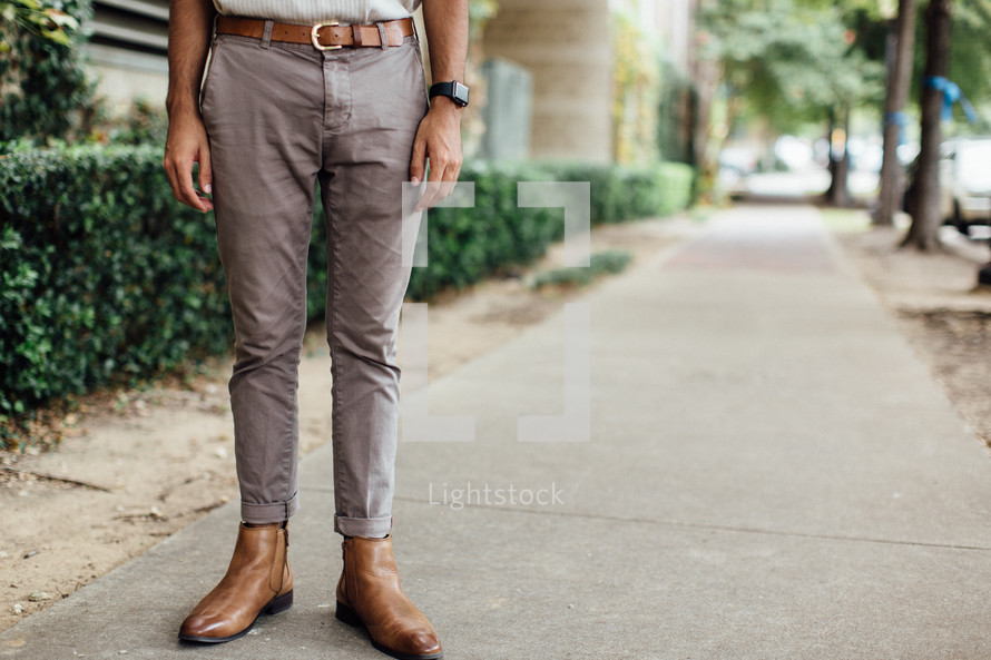 legs of a man standing on a sidewalk 