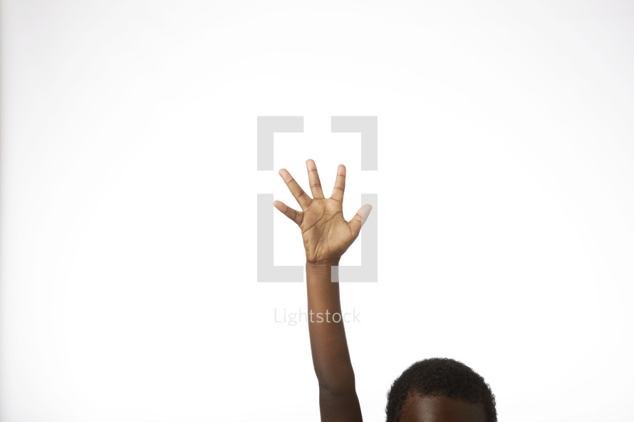 An African American boy with hand raised against a white background 