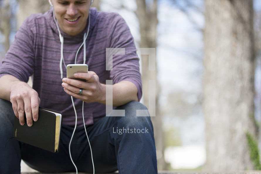 a man listening to a podcast holding a Bible 