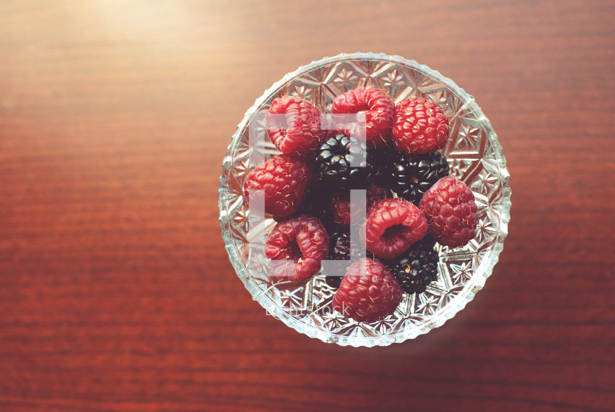 Raspberries and blackberries in a crystal dish.