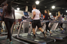men and women walking on treadmills at the gym