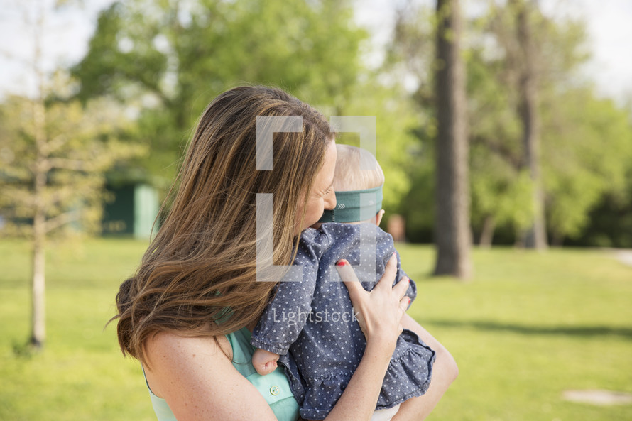 a mother holding her infant daughter outdoors 