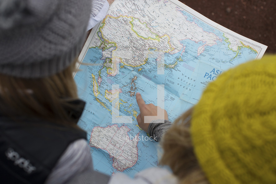 Two women looking at a map of the world.