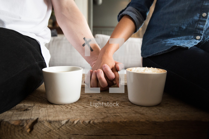 a couple holding hands and mugs of hot cocoa 